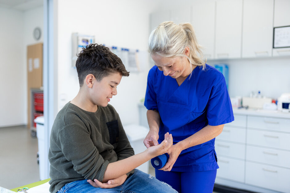 Eine Junge bekommt einen Verband um die Hand